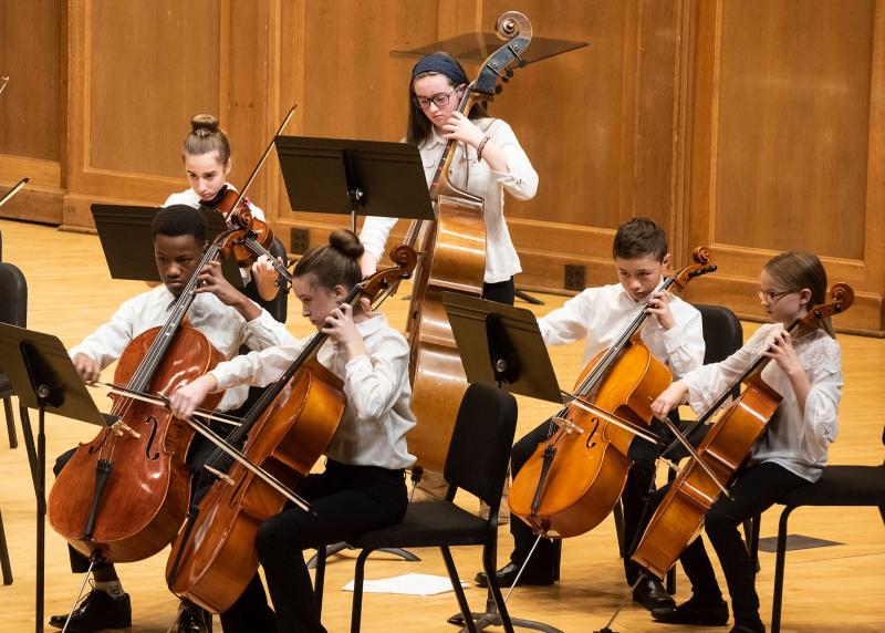 LYSO students play string bass, cello, and viola onstage during a concert.