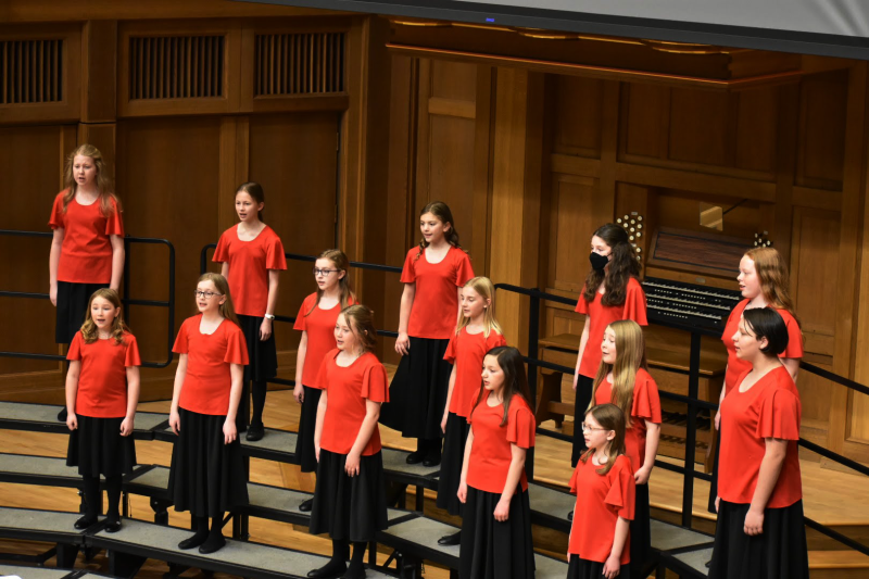 Singers performing in chapel with red and black dresses