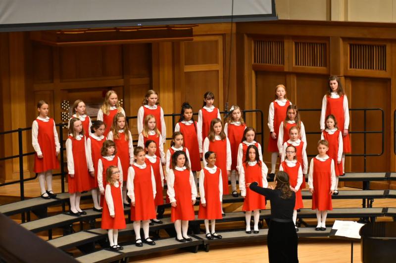 Primo choir singers performing on chapel stage in red jumpers