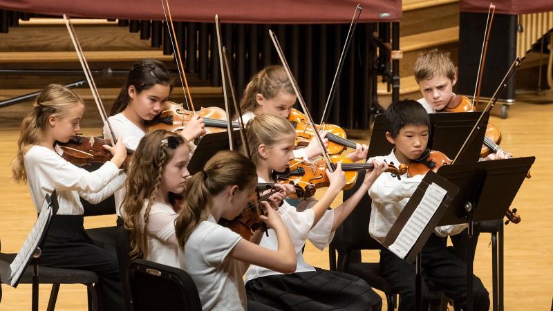 LYSO students play string instruments on stage during a concert.