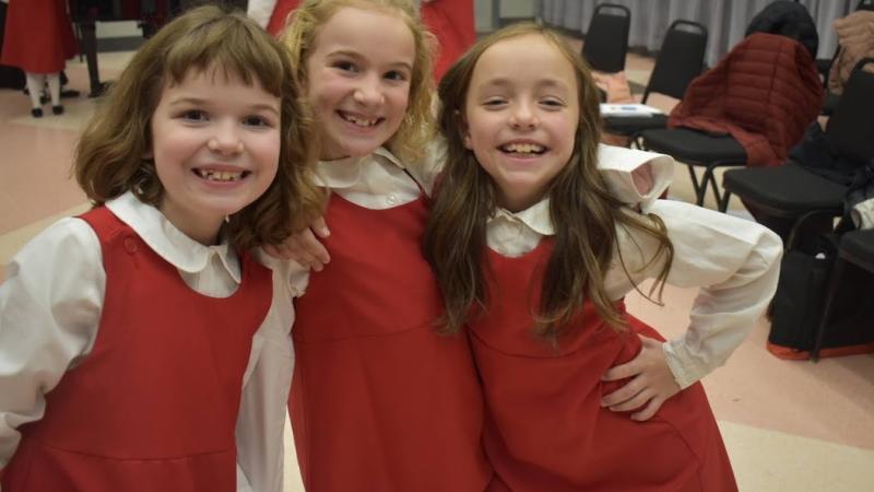 3 young singers wearing red Girl Choir t-shirts performing
