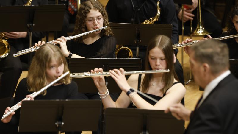 3 flutists and a conductor on stage at the Chapel.