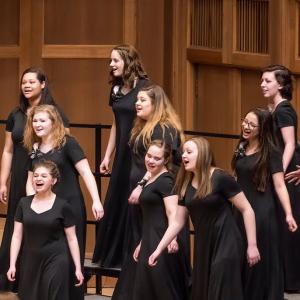 High school Bel Canto singers sing joyfully onstage during a concert.